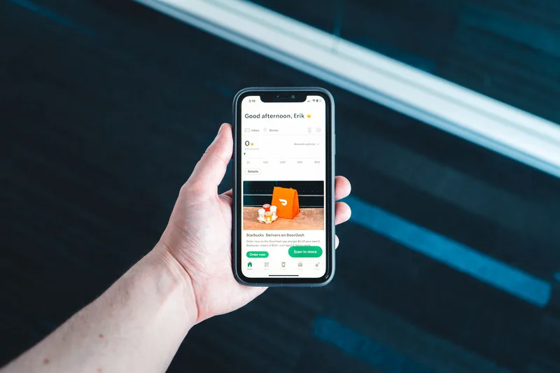 Seseorang memegang smartphone dengan tampilan aplikasi pengiriman atau pelacakan pesanan online