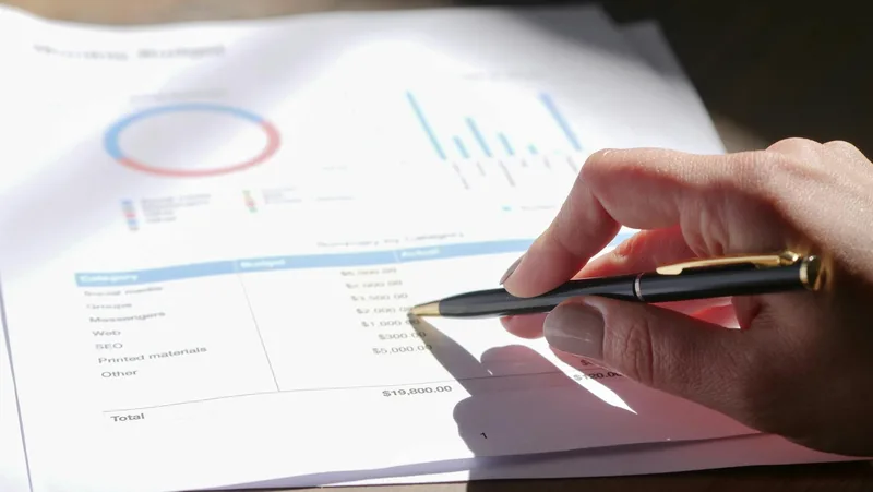Dokumen laporan keuangan dan spreadsheet akuntansi di atas meja kerja untuk pembukuan bisnis online
