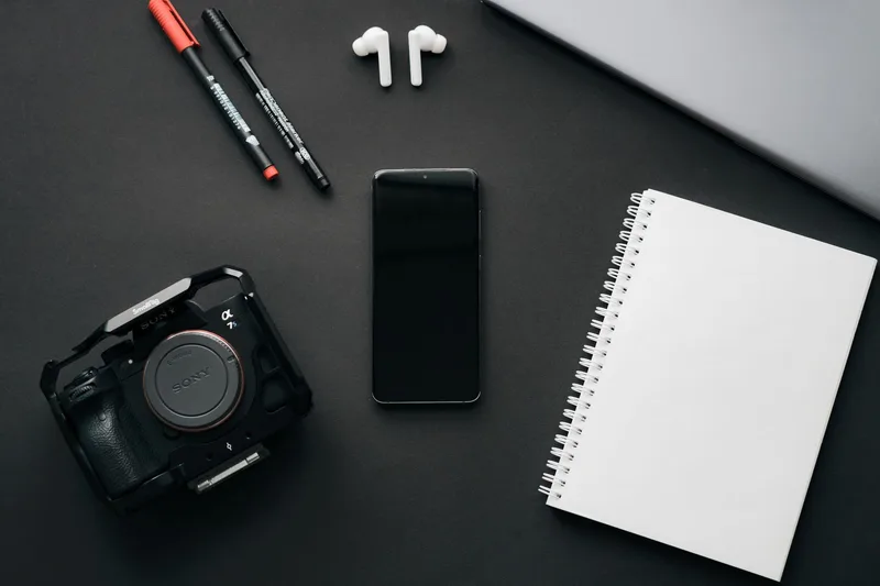 Flatlay kamera, smartphone, dan notebook untuk referensi foto produk jualan online