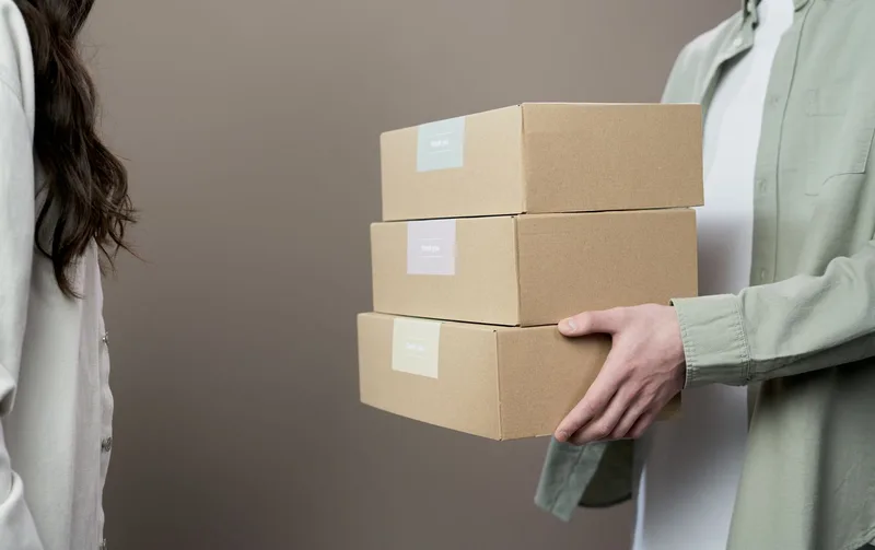 Dua orang saling menyerahkan paket kardus