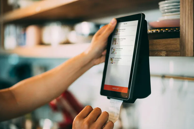 Seseorang memeriksa transaksi digital di perangkat payment terminal sebagai ilustrasi cek riwayat pesanan