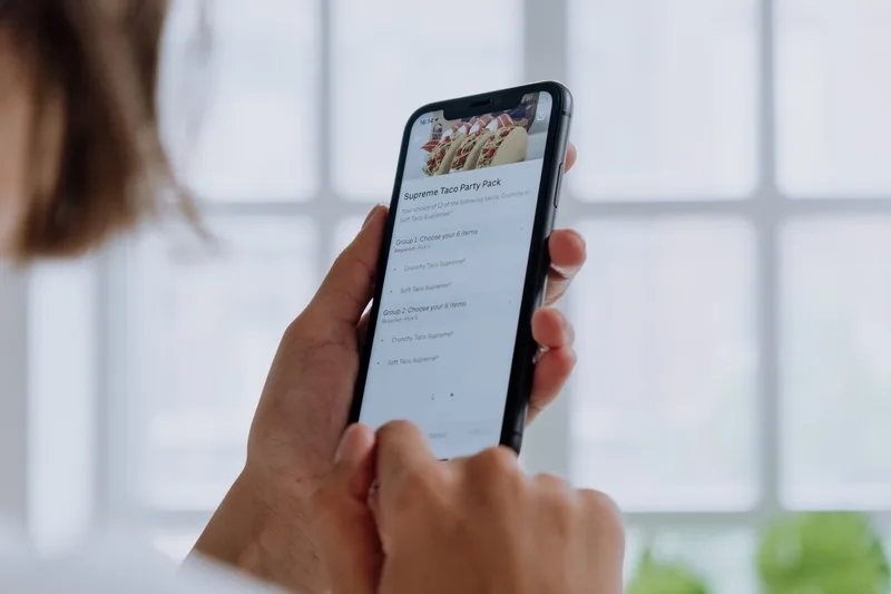 Close-up tangan menggunakan smartphone untuk memeriksa status pesanan di aplikasi belanja online