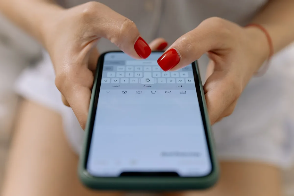 Tangan menggunakan smartphone untuk mengetik pesan, ilustrasi mengirim link Shopee lewat WhatsApp