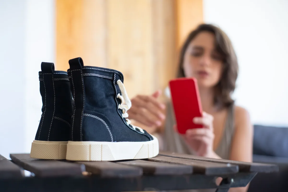 Pemilik usaha kecil memotret sepatu dengan smartphone untuk diposting sebagai listing produk online