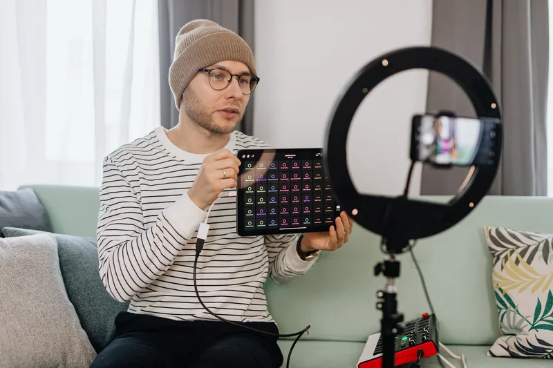 Lelaki merakam video ulasan produk menggunakan telefon pintar dan ring light