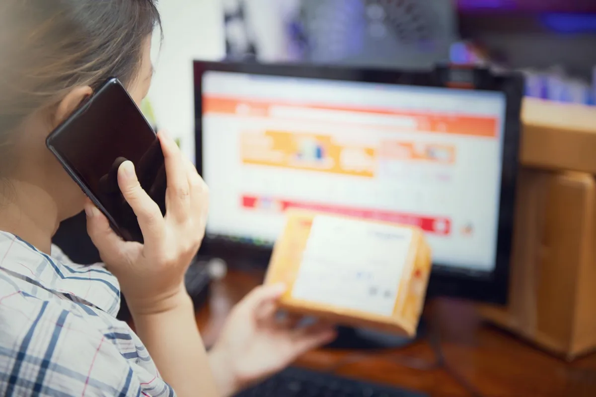 Filipino seller setting up a Shopee seller account on smartphone with product packaging materials nearby