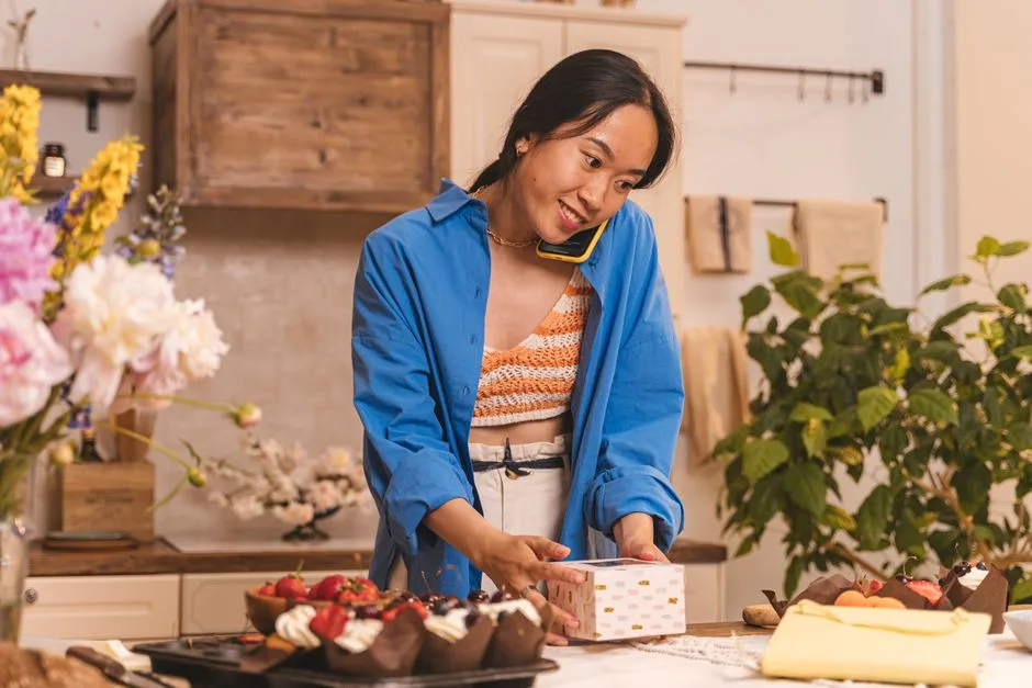 Small business owner in Malaysia boxing up a product order while taking a call