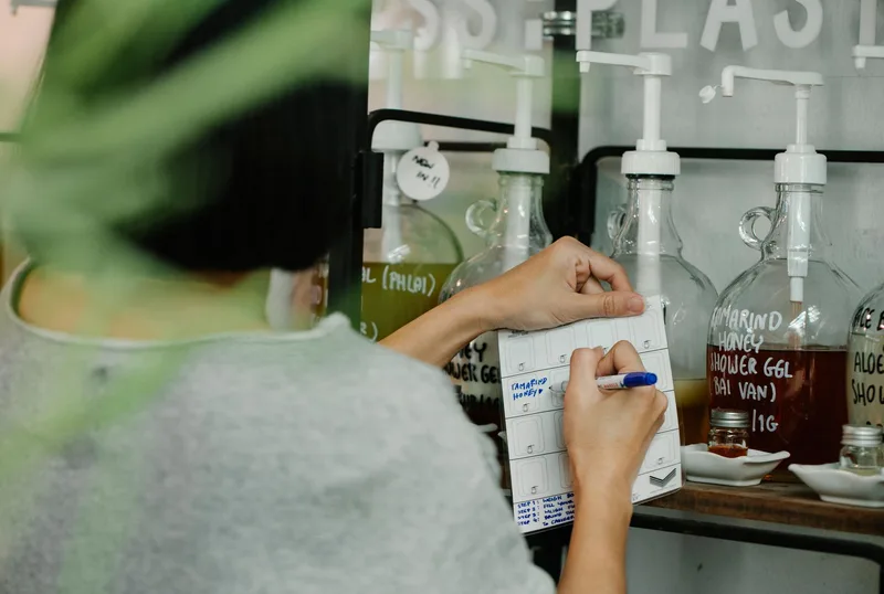 พนักงานร้านค้าตรวจสอบสต็อกสินค้าโดยจดบันทึกรหัสสินค้าในสมุด